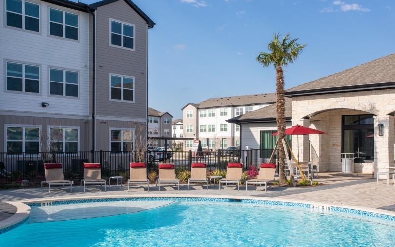 a pool with chairs and umbrellas by a building